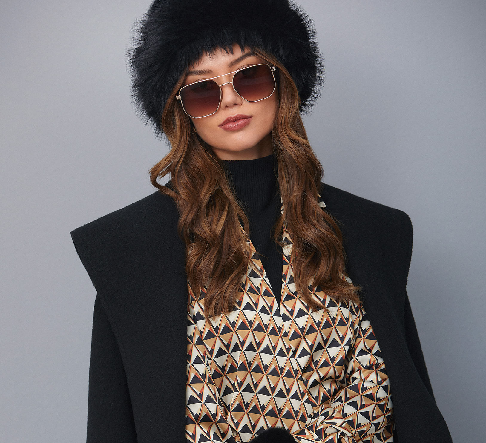 Foto de modelo usando blazer negro y chaqueta estampada, gorro y gafas de la marca Studio F